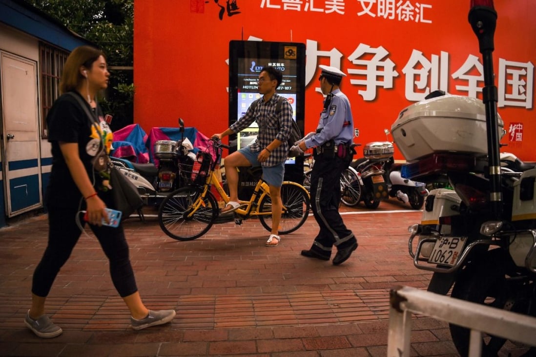 A traffic police officer prepares to talk to a man on a bicycle near a facial recognition screen at an intersection in Shanghai. (Picture: AFP)