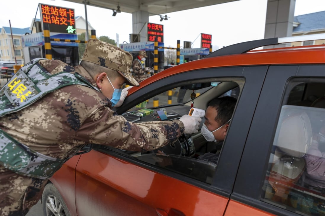 A member of China’s militia arm of the armed forces uses a digital thermometer to take a driver's temperature at a highway tollgate in Wuhan on January 23. (Picture: Chinatopix)