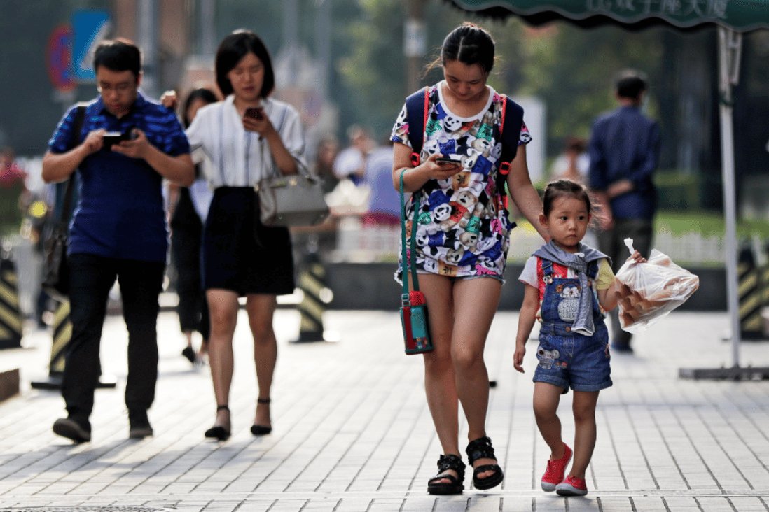 Pedestrians view their smartphones on a sidewalk in Beijing. (Picture: Andy Wong/AP Photo)