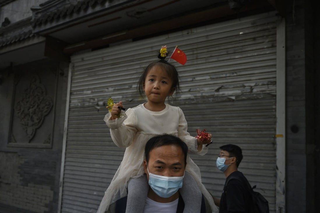 A Chinese father carries his daughter while visiting a commercial and tourist area in Beijing on October 3, 2020. Photo: Getty Images