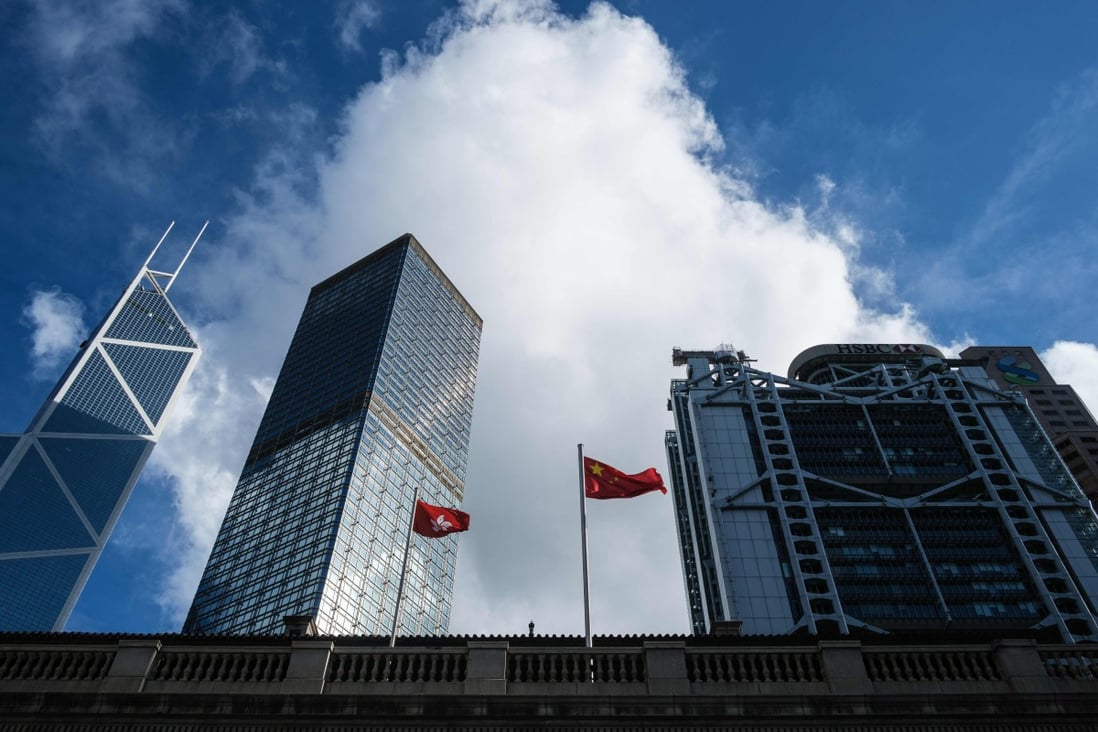 The Chinese national flag and the Hong Kong flag are flanked by skyscrapers housing the international banks and financial institutions that the city is famed for. Photo: AFP