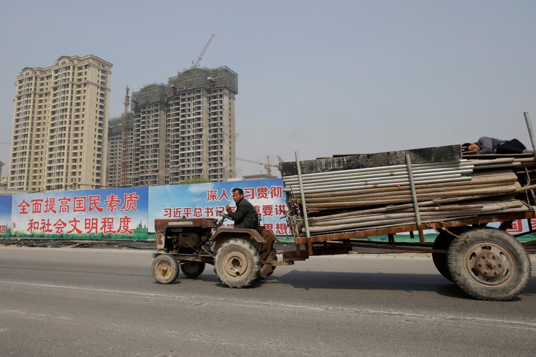 A man drives a tractor carrying building materials past a property under construction in Xiongxian county, Hebei province, China. Photo: Reuters