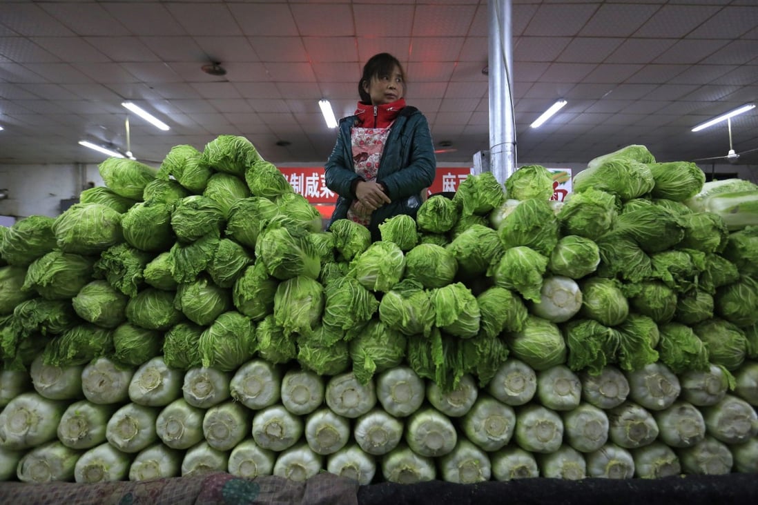A seller stands behind a pile of vegetables at a market in Beijing, China on April 11, 2016. Photo: EPA