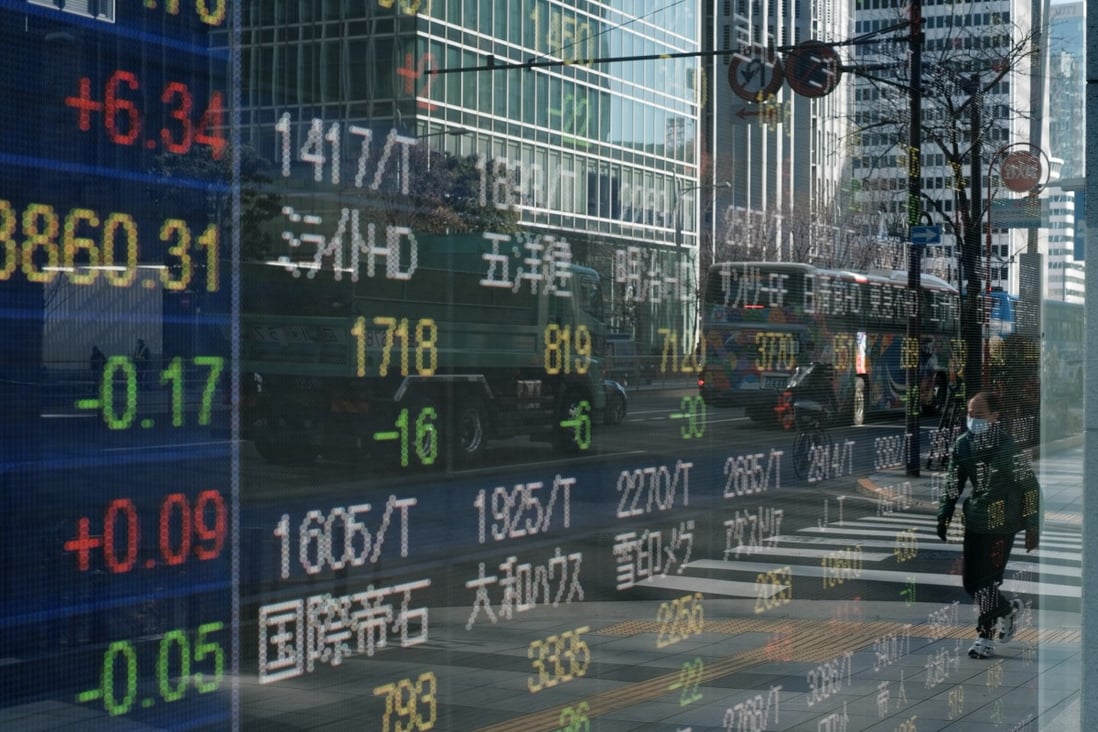 A pedestrian wearing a protective mask reflected on an electronic stock board outside a securities firm in Tokyo. Photo: Bloomberg