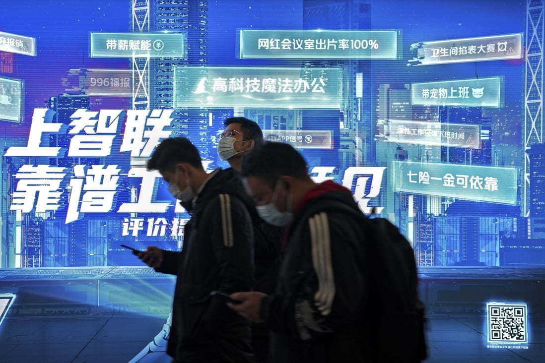 Commuters browse their smartphones as they walk by a mobile phone app advertisement at a subway station in Beijing. Photo: AP