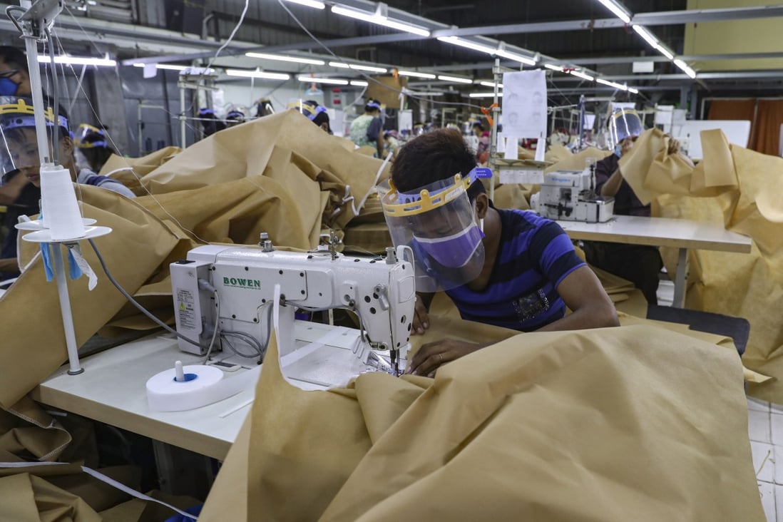 A man wearing face mask and face shield to help curb the spread of the new coronavirus, sews surgical gown at a garment factory in Yangon, Myanmar. Garment workers in Myanmar are urging major international brands to denounce the recent military coup there and put more pressure on factories to protect workers from being fired or harassed. Photo:AP