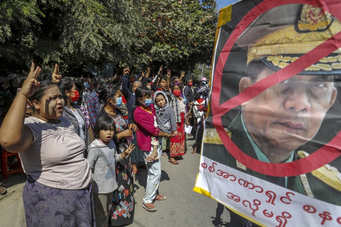 Anti-coup protesters stand near a defaced image of military chief Senior General Min Aung Hlaing in Mandalay. Photo: AP