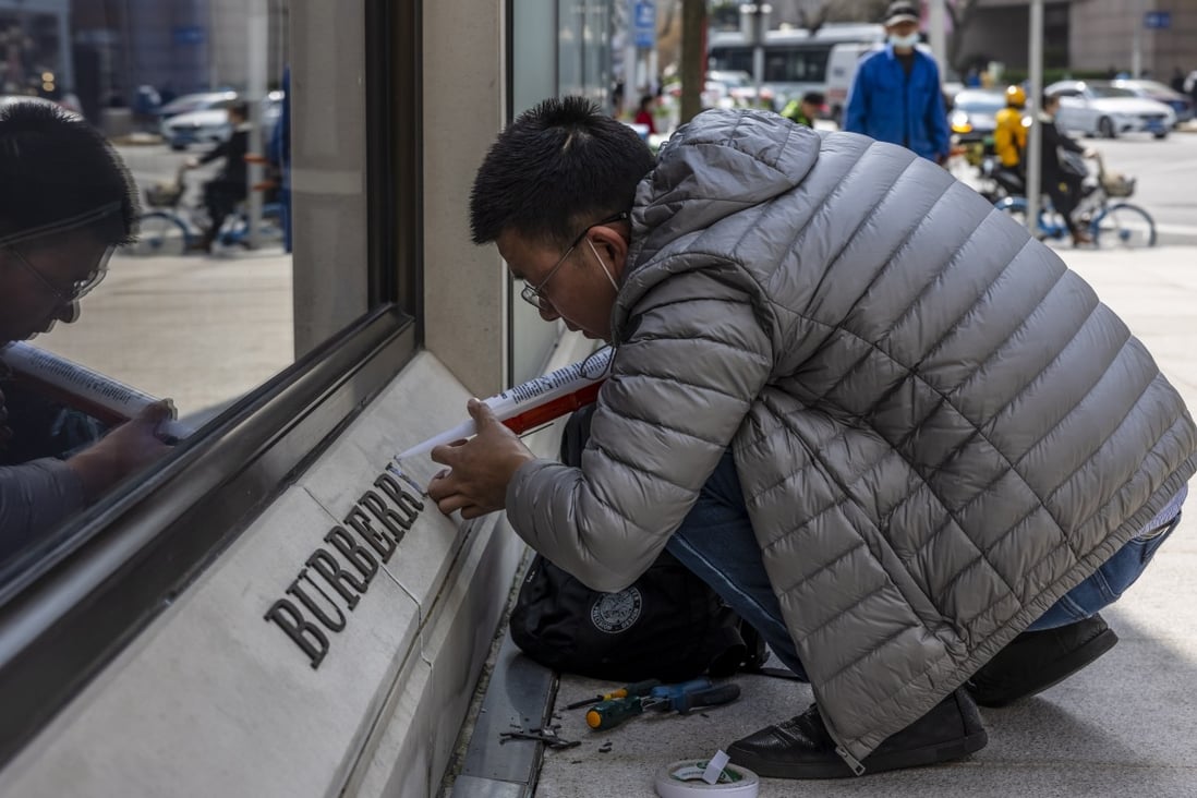 A man repairs a damaged logo in front of the Burberry store in Shanghai on March 26. Burberry,  Fila, Hugo Boss, H&M, Nike and Adidas have been targeted for refusing to buy Xinjiang cotton over concerns of forced labour in the region.  Photo: EPA-EFE