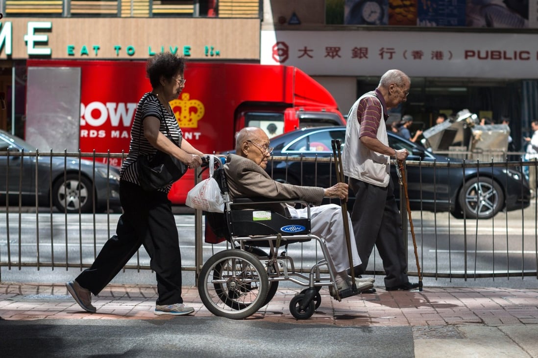 A woman pushes an elderly man on a wheelchair, on a sidewalk in Central district, Hong Kong on 13 September 2017.Photo EPA-EFE