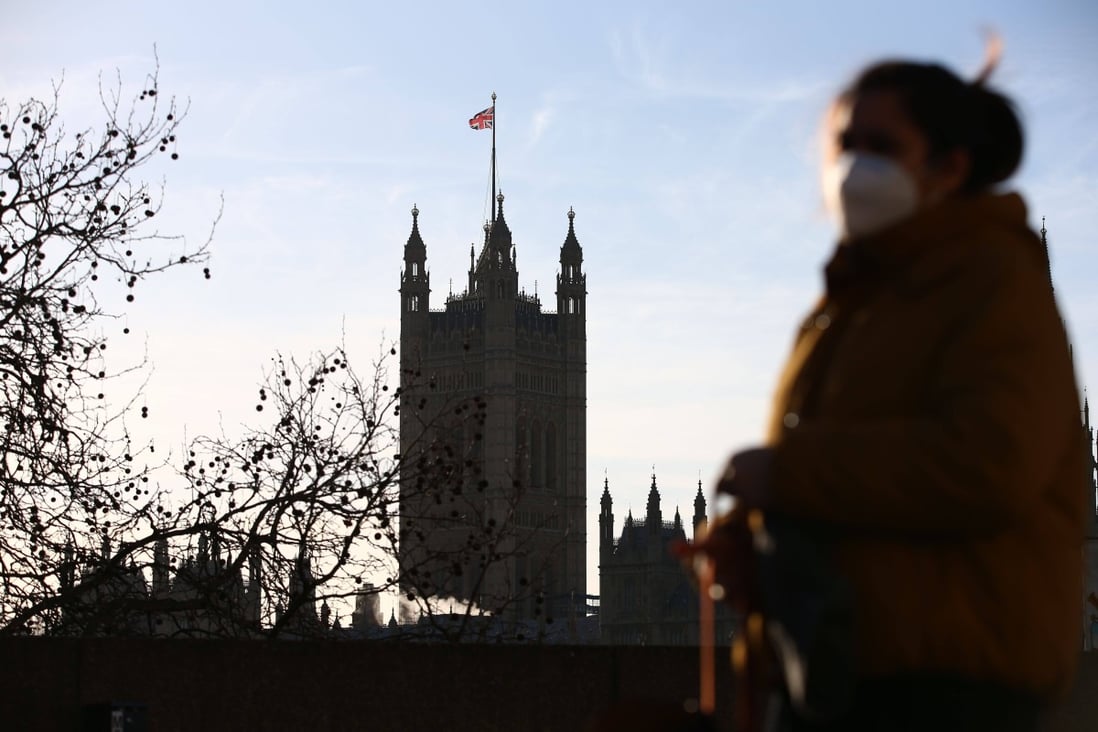 A woman walks through central London with the Houses of Parliament in the background. Photo: AFP