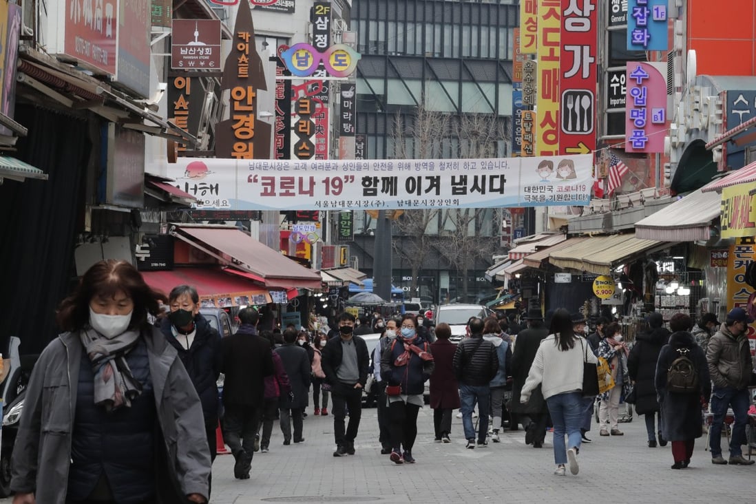 People wearing face masks walk through a market in Seoul, South Korea. Photo: AP