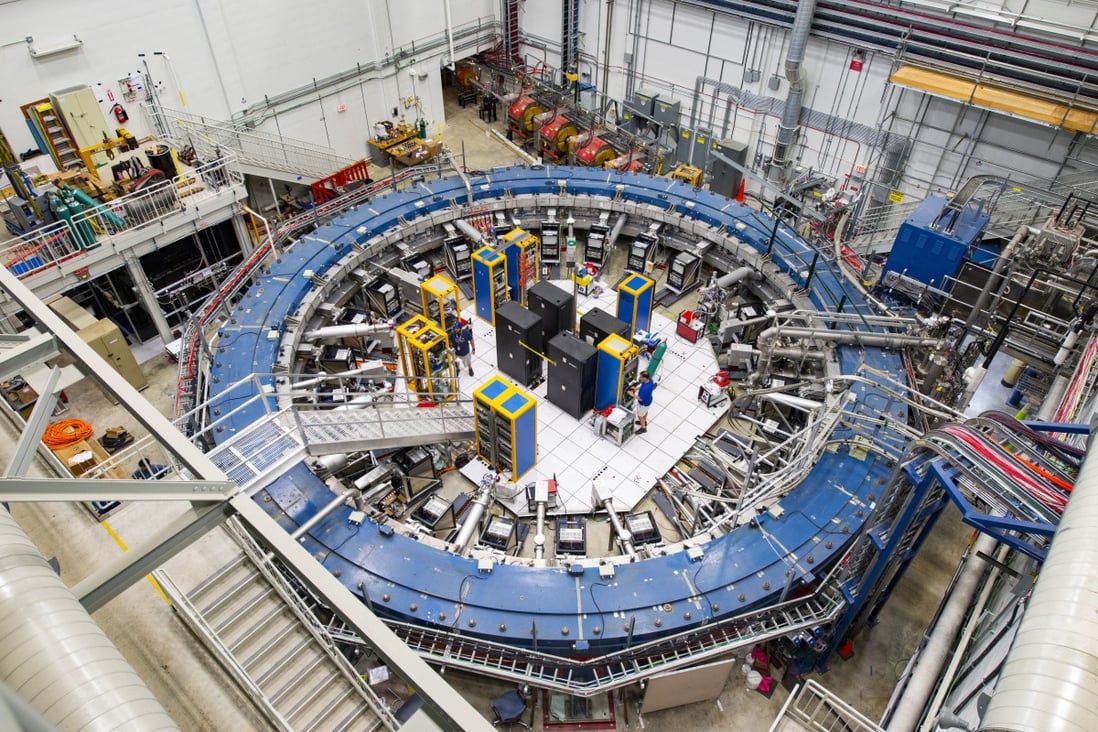 The Muon g-2 ring sits in its detector hall amids electronics racks, the muon beamline, and other equipment. The experiment studies the precession (or wobble) of muons as they travel through the magnetic field. Photo: Fermilab