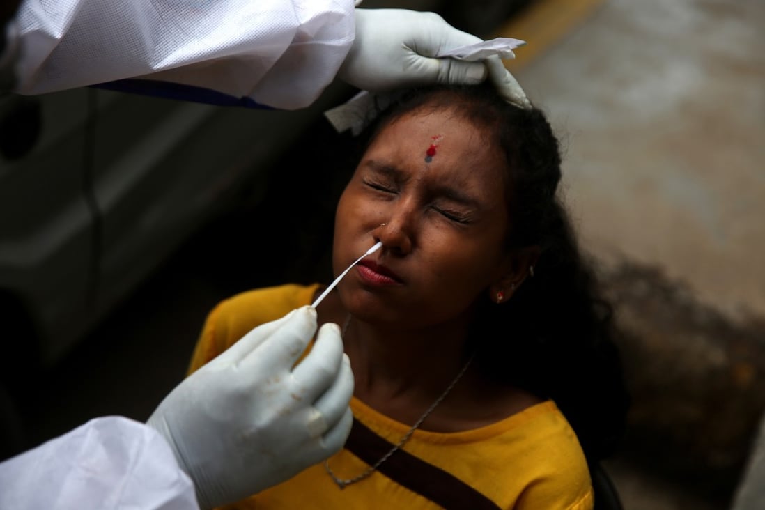 An Indian health worker collects a nasal swab sample from a woman in Bangalore. Photo: EPA