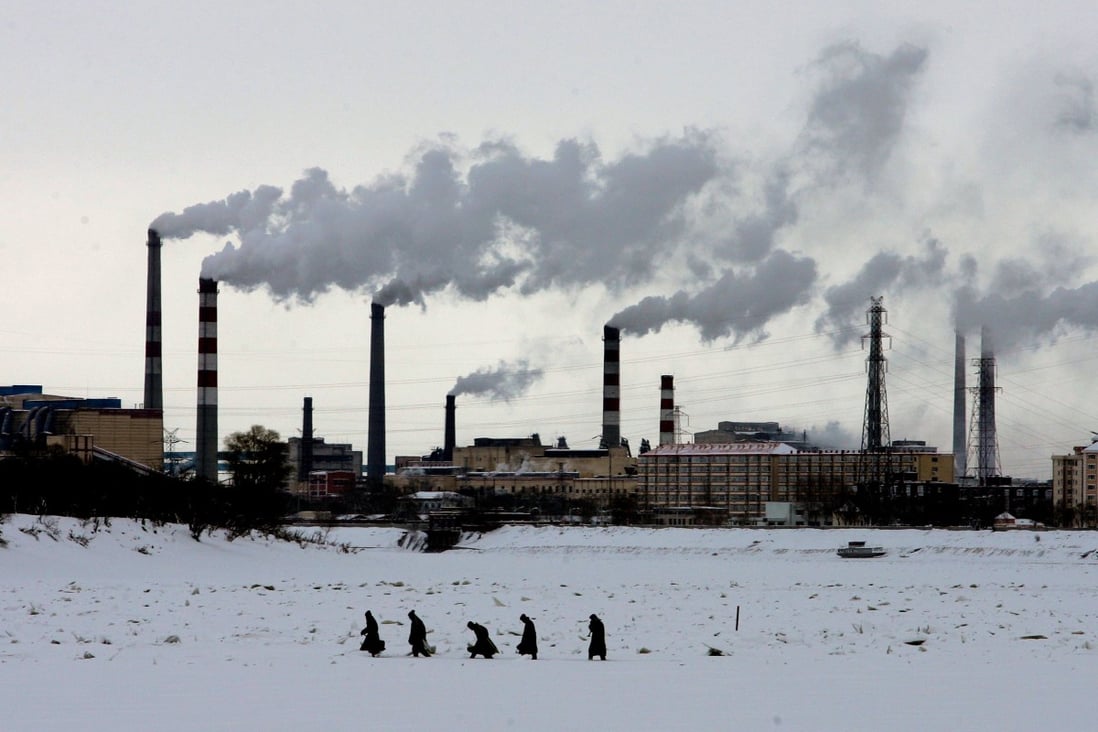 Residents walk across the frozen Songhua River in front of smoke stacks at Jiamusi, in China’s northeast Heilongjiang province on December 4, 2005. Photo: AP