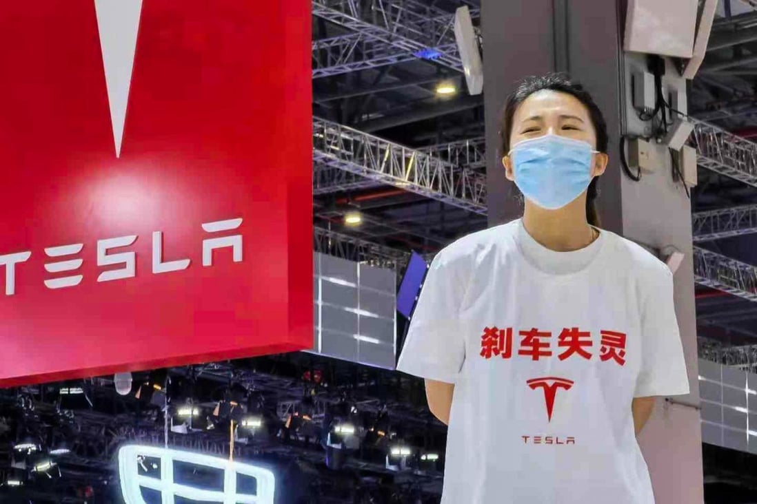 A photo from Chinese social media went viral showing the woman at the Shanghai Auto Show 2021 standing on a Tesla sedan wearing a white T-shirt marked with Chinese characters reading “brake malfunction” and a Tesla logo on Monday. Photo: Handout