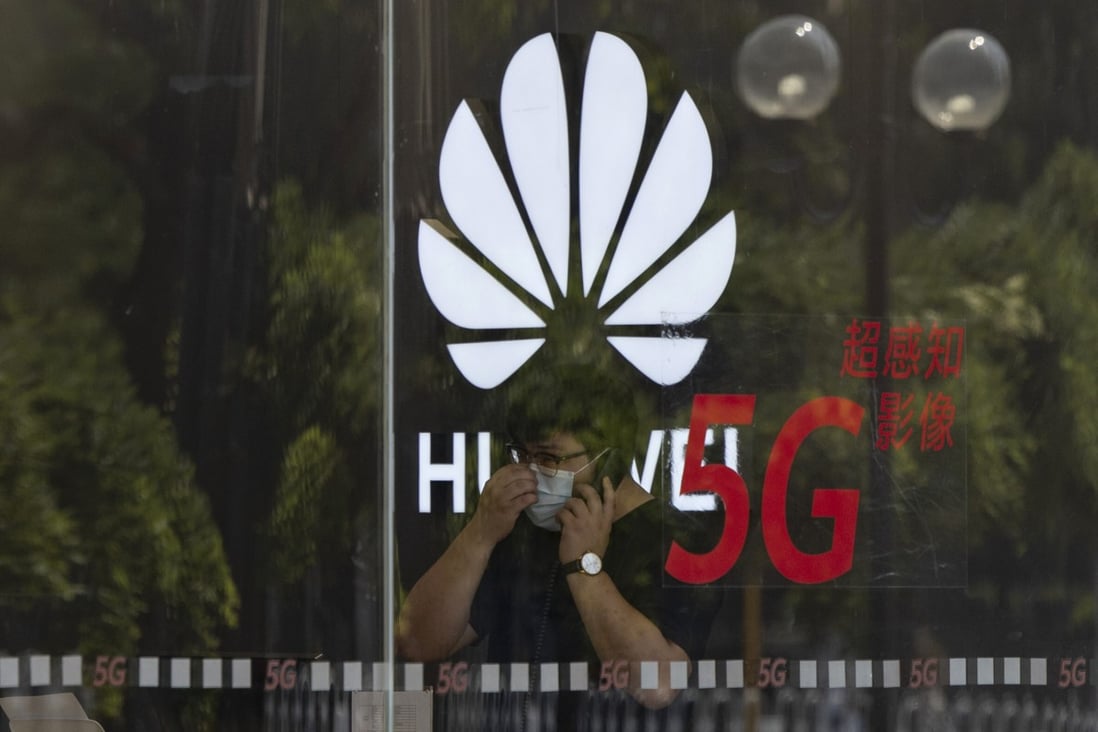 A worker wearing a mask speaks on the phone near the Huawei logo in a store in Beijing. Photo: AP
