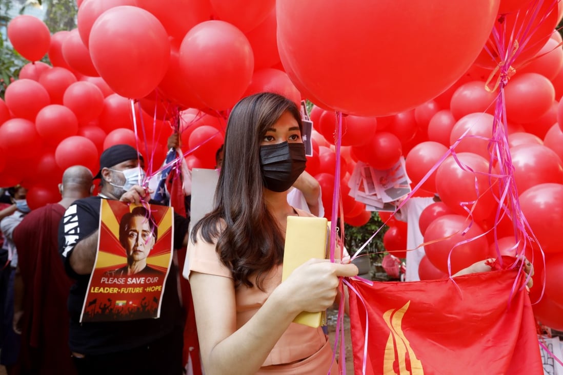 Protesters hold placards and a flag of the National League for Democracy party attached to red balloons during a demonstration against the military coup in Yangon, Myanmar. Photo: EPA