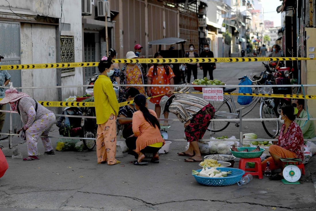 People buy vegetables next to a barricade set up in a neighbourhood due to lockdown restrictions introduced to try to halt a surge in cases of the Covid-19 coronavirus in Phnom Penh. Photo: AFP
