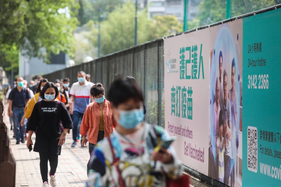 People walk past a poster in Causeway Bay encouraging the public to take the Covid-19 vaccine. Photo: Xiaomei Chen