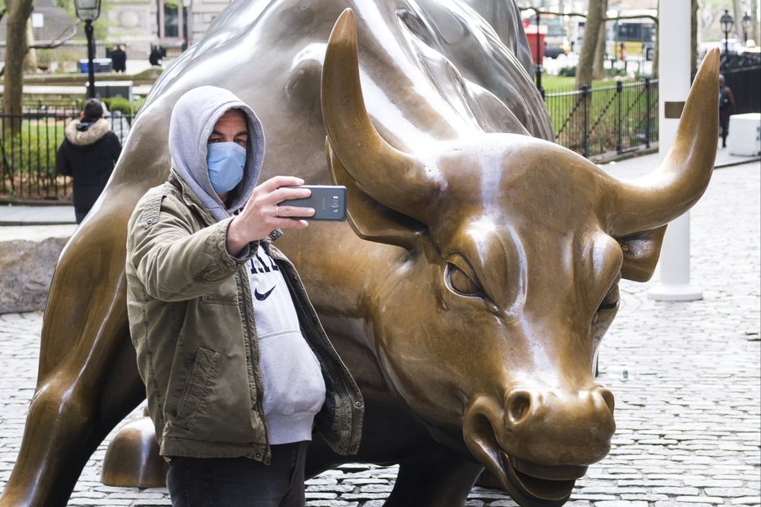 A man in a protective mask takes a selfie with the Charging Bull statue on Broadway in New York. Photo: EPA-EFE