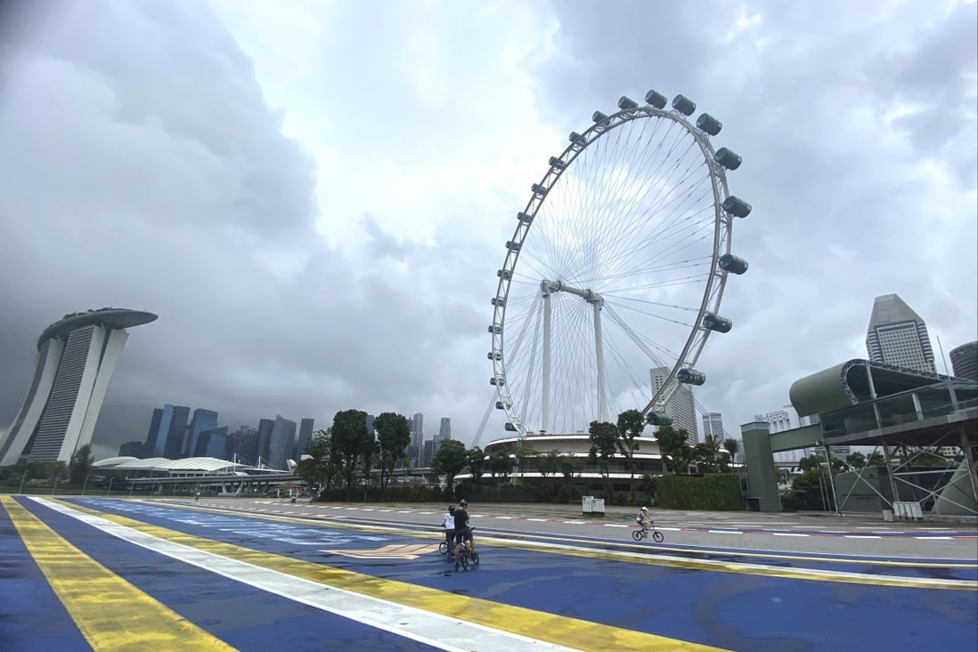 Cyclists pass the Singapore Flyer Ferris Wheel attraction. Photo: AP