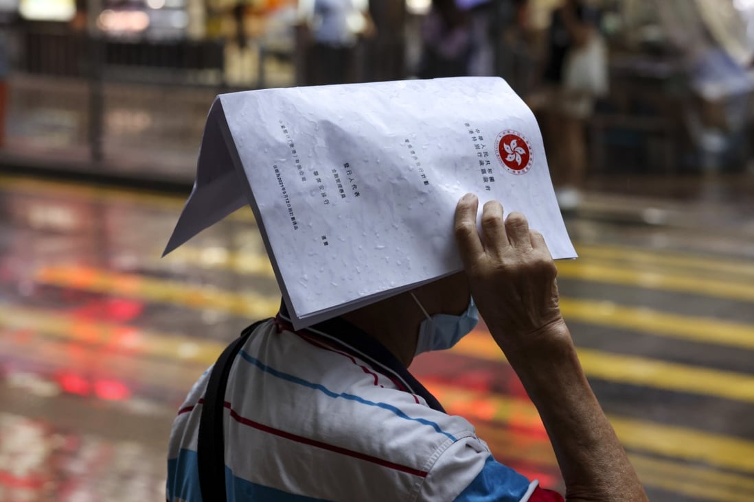 A man holds an iBonds subscription document over his head during heavy rain in Mong Kok on June 1. Photo: Nora Tam