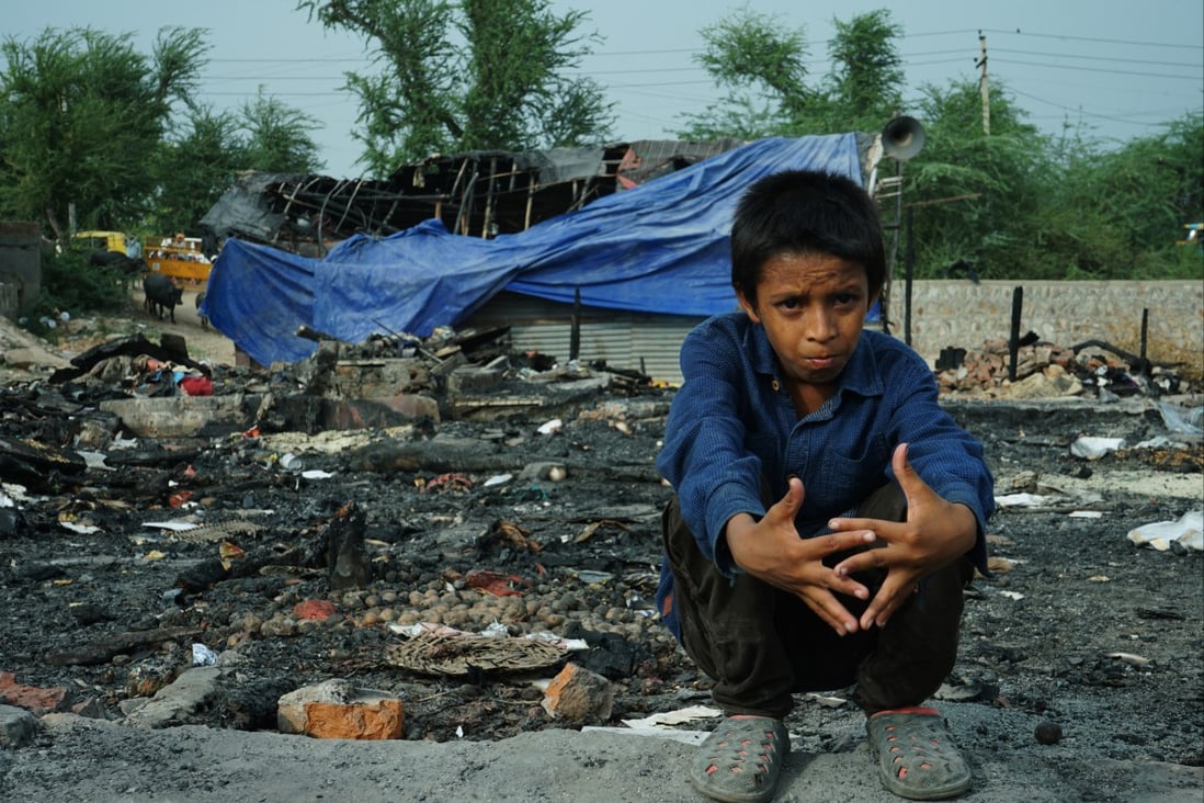Rohingya refugee Mohammad Ismail sits amid the charred remains of his family’s shelter in New Delhi, in front of the community’s burnt-out mosque. Photo: Adnan Bhat