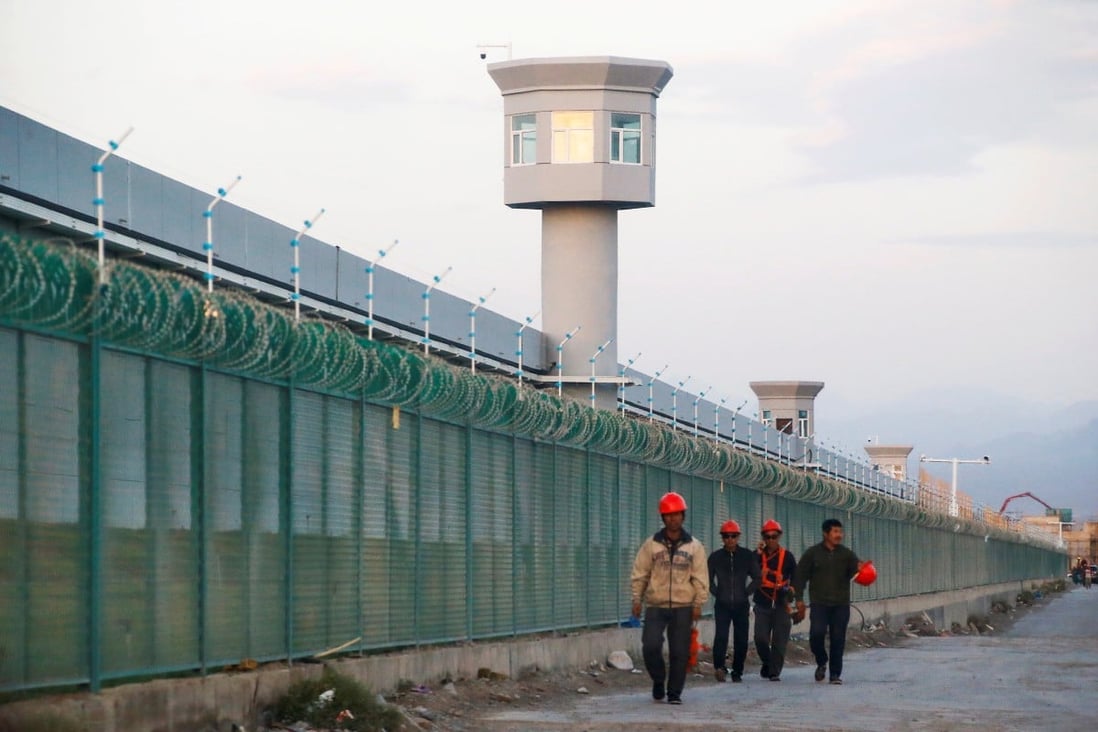 Workers walk along a perimeter fence of what officials call a vocational skills education centre in Dabancheng in Xinjiang. Photo: Reuters
