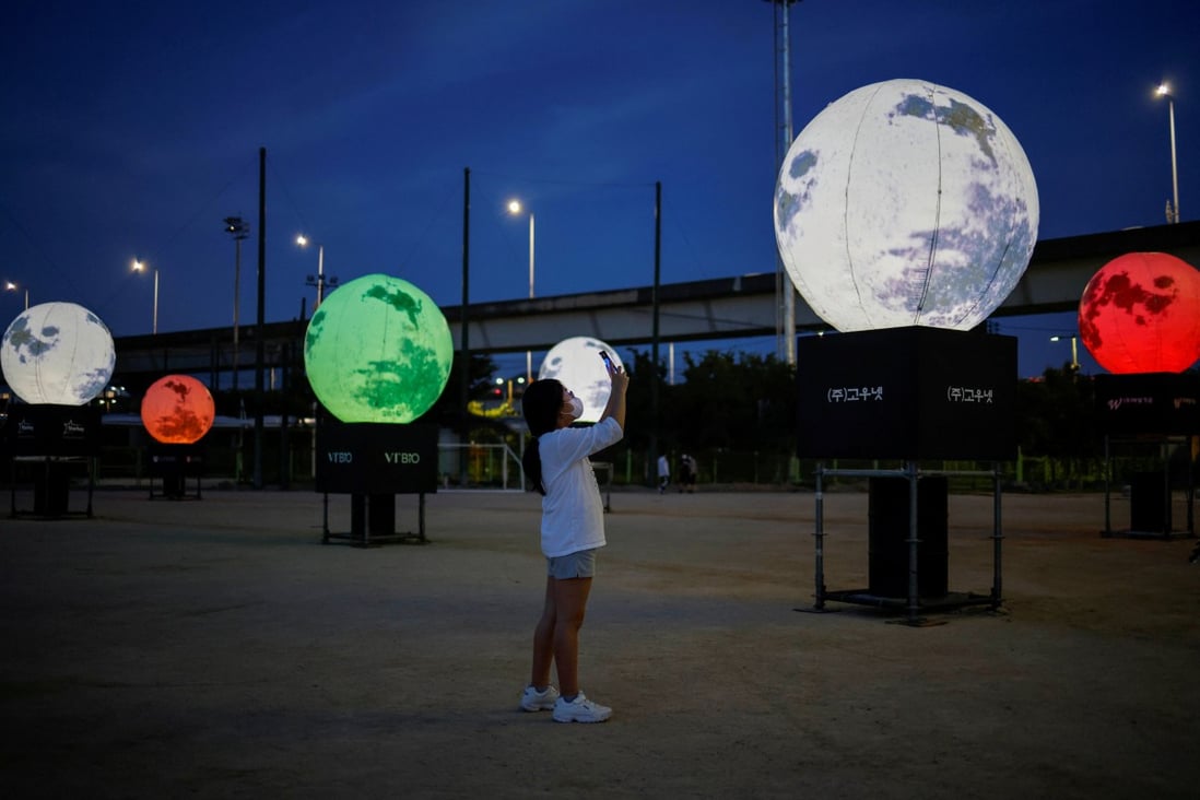 A girl takes a picture of artificial full moons installed at a park as a wish to overcome the coronavirus pandemic and celebrate the Chuseok holiday, the Korean Thanksgiving Day, in Seoul, South Korea, on September 21, 2020. While national rivalries fostered innovation during the Cold War space race, they can also stymie it. Photo: Reuters