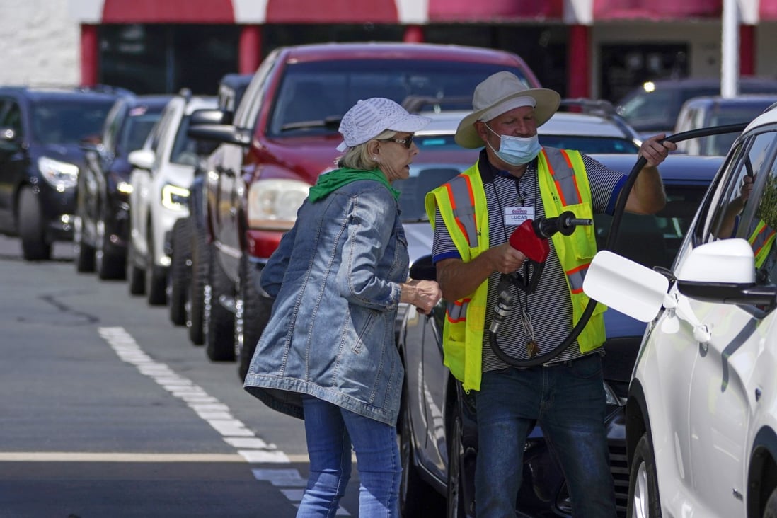 A customer gets help pumping gas at Costco, as others wait in line, on May 11 in Charlotte, North Carolina. Colonial Pipeline, which delivers about 45 per cent of the fuel consumed on the east coast, halted operations after revealing a cyberattack that it said had affected some of its systems. Photo: AP