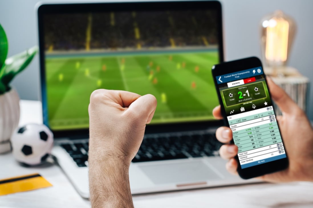 A fan cheers for his favourite team as he watches a game on his laptop, while making bets at bookmaker’s website. Photo: Shutterstock 