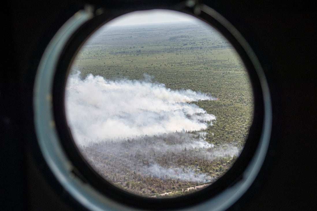 Smoke rises from fires at a palm oil plantation, as seen from the window of a water bombing helicopter of the Local Disaster Management Agency (BPBD) during an operation near Palembang, South Sumatra province, Indonesia, on July 26. Photo: Reuters 