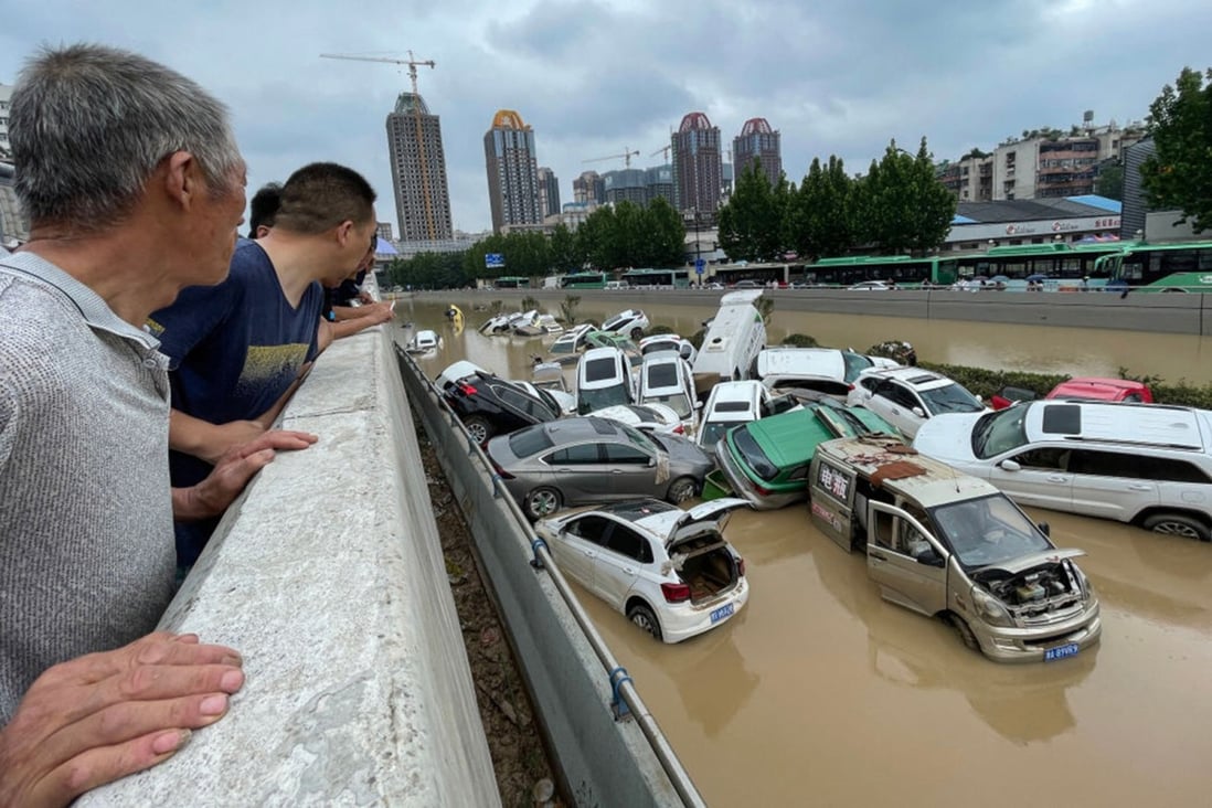 People look out at cars sitting in floodwater after heavy rains hit the city of Zhengzhou in Henan province on July 21. Photo: TNS 