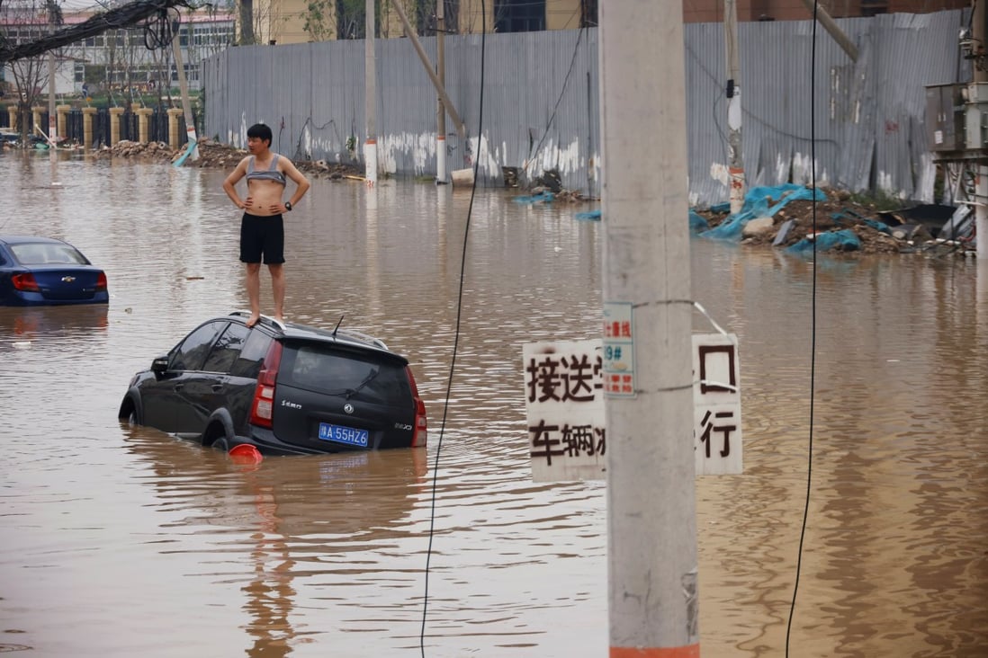 A man stands on a stranded car on a flooded road after heavy rainfall in Zhengzhou, Henan province, China, on July 22. More than 290 have died as a result of the unprecedented flash floods. Scientists warn that more such extreme weather can be expected. Photo: Reuters