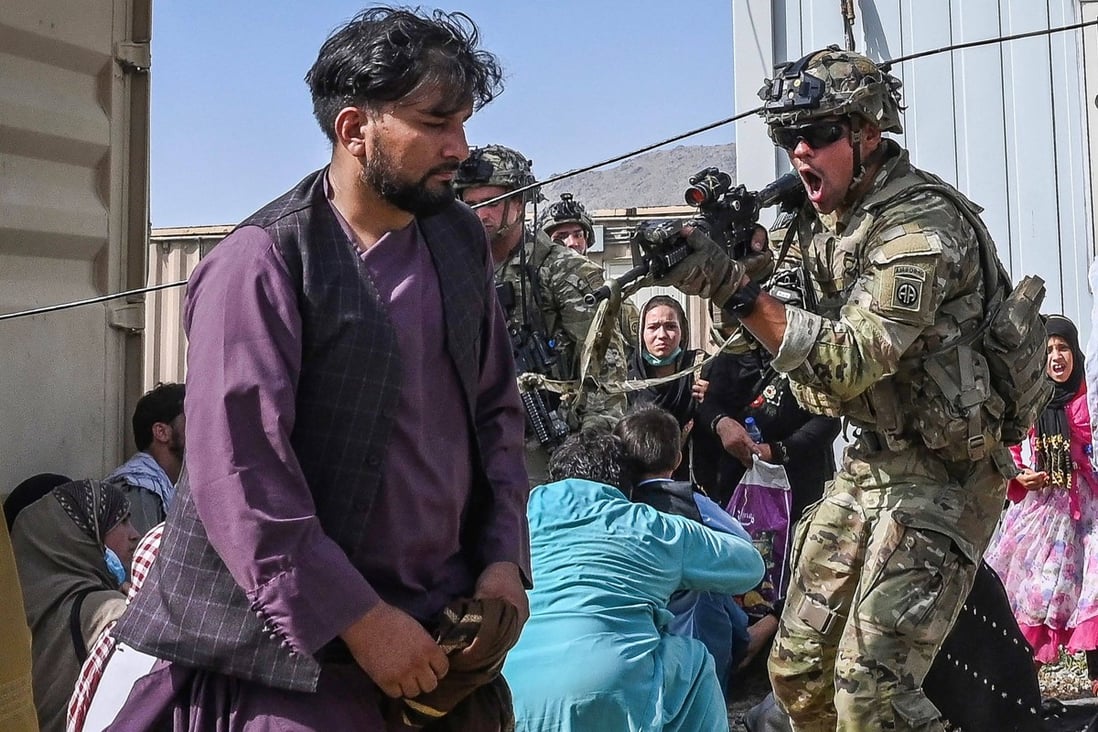 A US soldier points his gun at an Afghan passenger at the airport in Kabul on August 16, as people mob the airport to flee hardline rule after the Taliban’s swift takeover of the capital. Photo: AFP