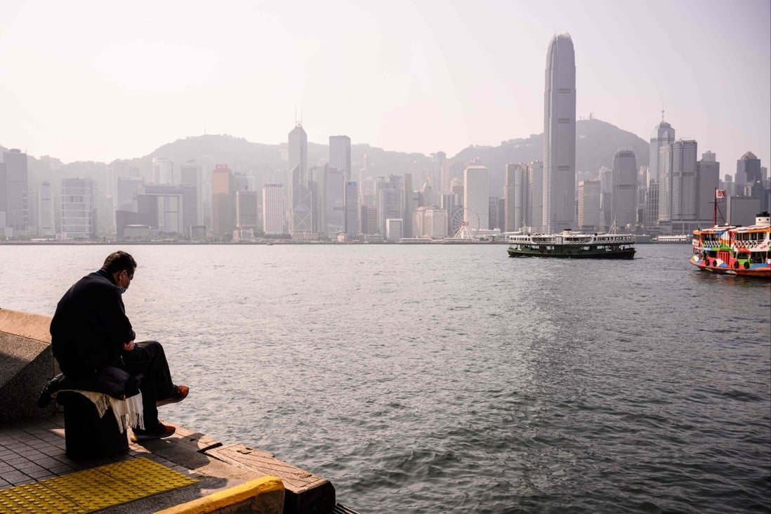 A man sits on a bollard on the Kowloon side of Victoria Harbour in January 2021. Photo: AFP
