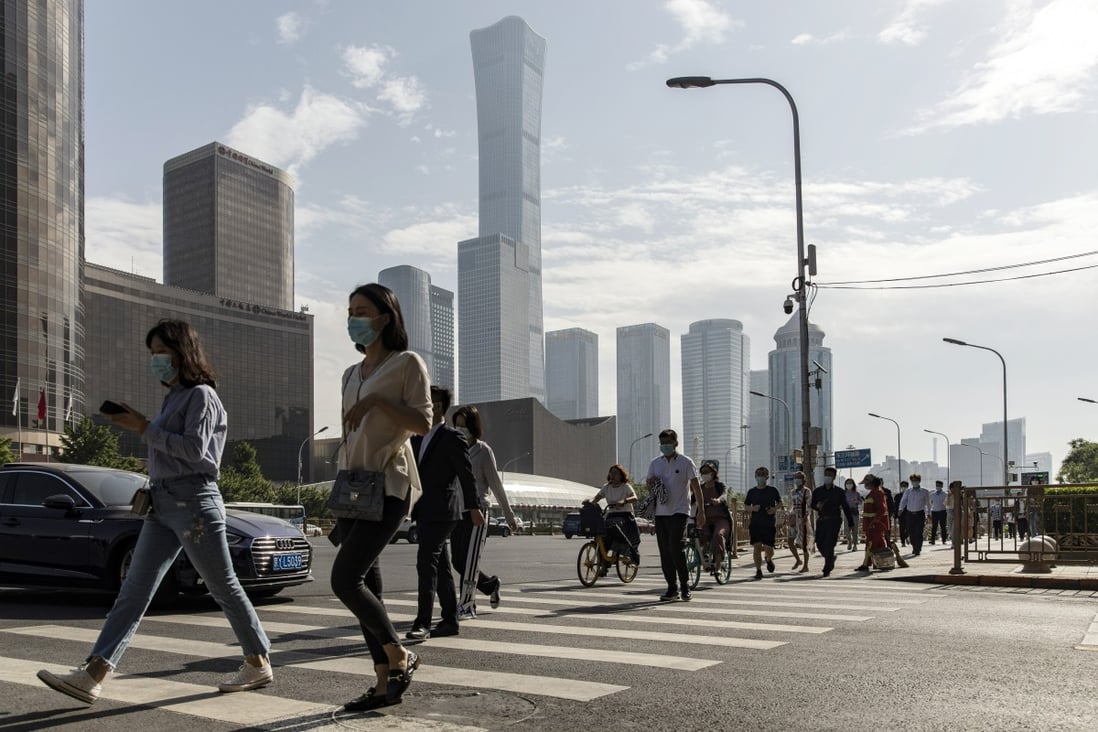 Pedestrians cross a road in Beijing’s central business district on May 27. Even as the Delta variant spreads across Asia, office re-entry rates have been high in Beijing, Shanghai and Hong Kong. Photo: Bloomberg  