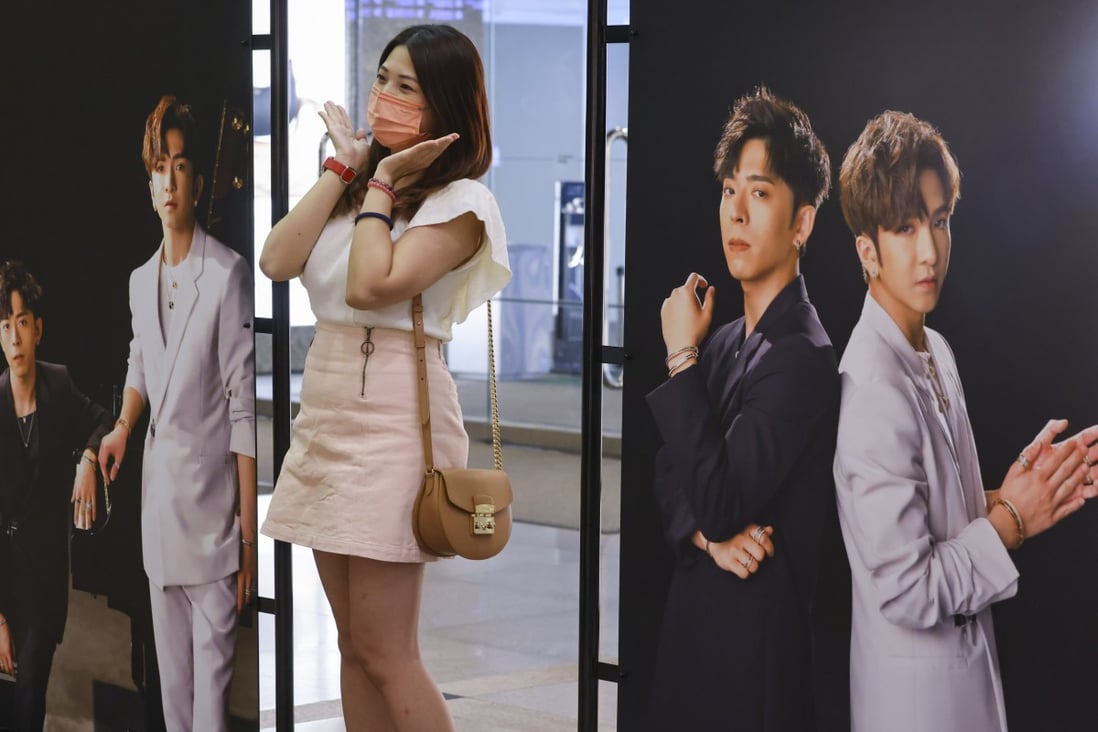 A woman poses with large portraits of members of the boy group Mirror, at an exhibition in Harbour City in Tsim Sha Tsui on September 11. Photo: Dickson Lee