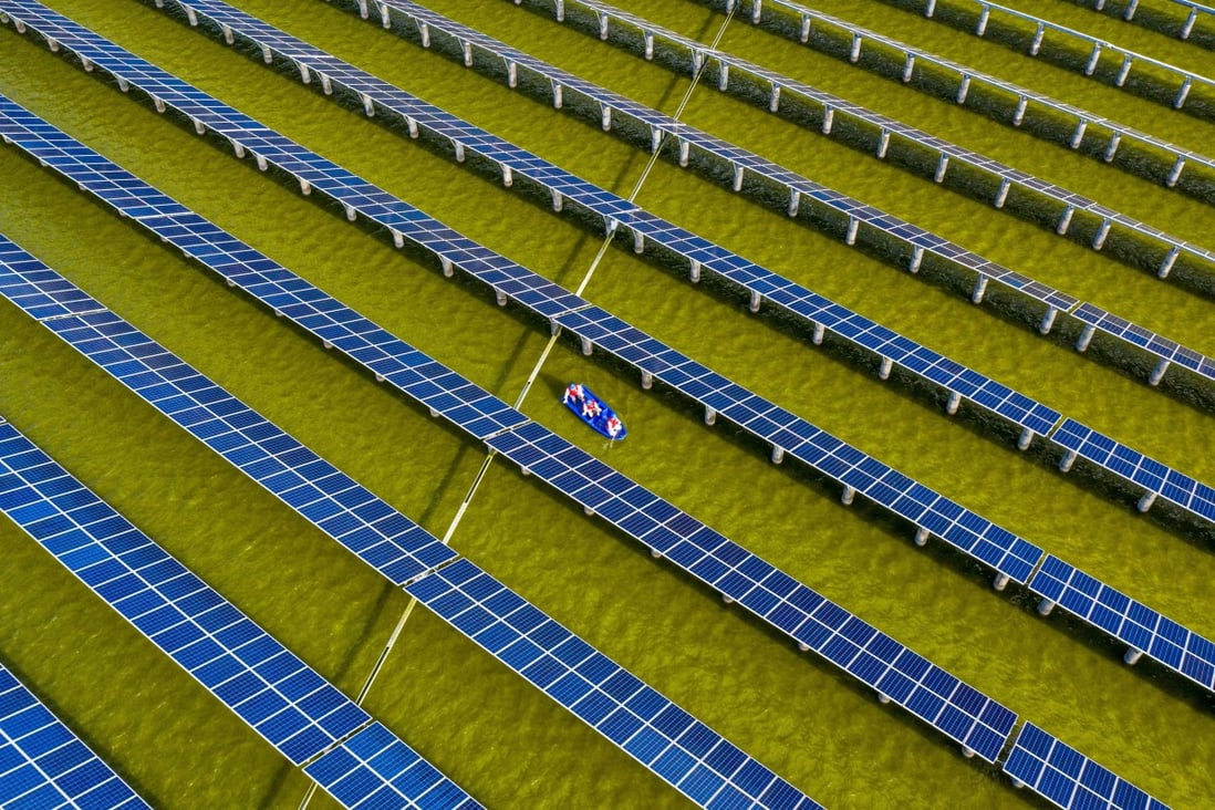 Electrical workers in a boat check solar panels at a photovoltaic power station built in a fishpond in Haian, eastern Jiangsu province, on July 19. Photo: AFP