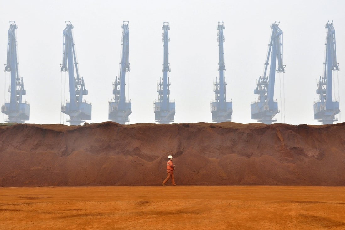 A worker passes a pile of iron ore from Australia at a port in Tianjin municipality, China. Photo: Reuters