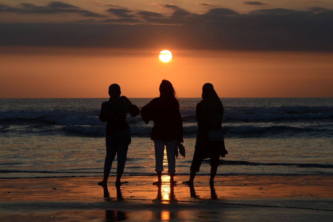 People watch the sunset at Kuta beach near Denpasar in Bali on October 7. The island’s international airport is set to reopen on October 14. Photo: AFP