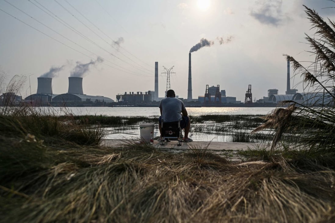 A fisherman sits by the Huangpu river across from the Wujing Coal-Electricity Power Station in Shanghai on September 28. Photo: AFP