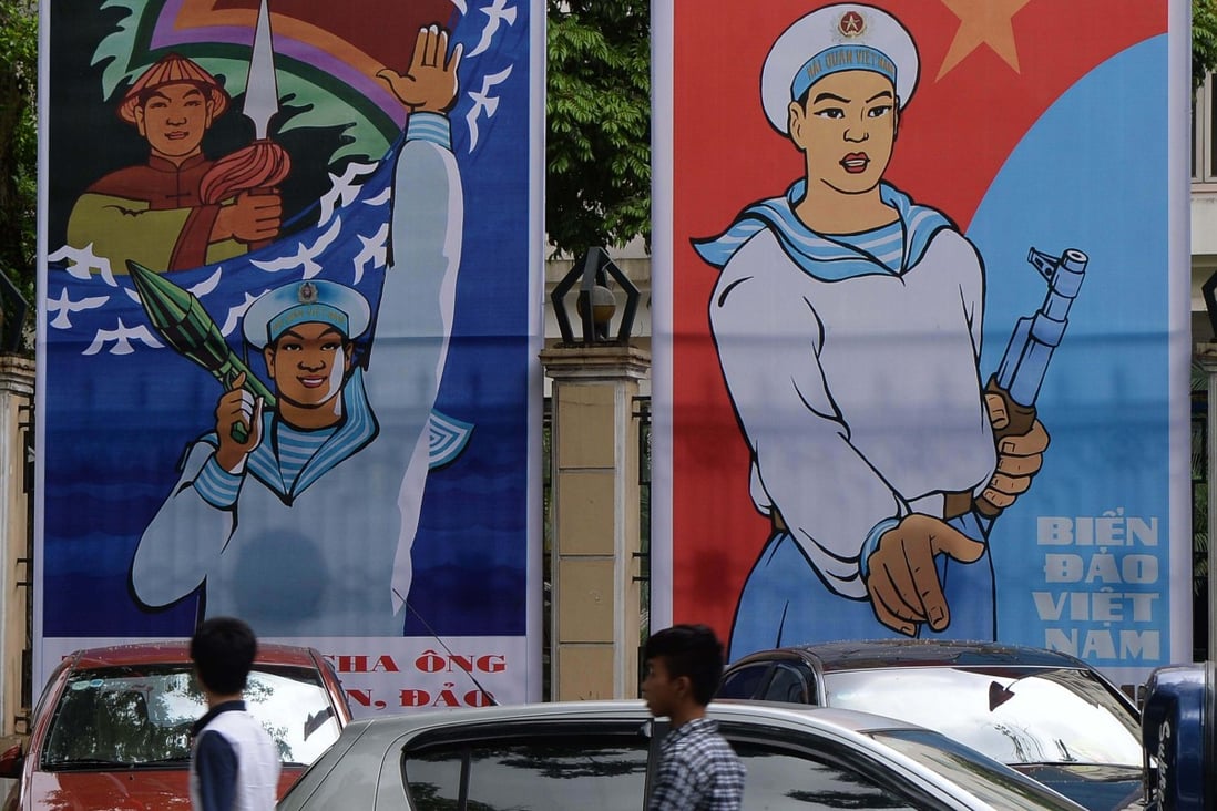 Young people walk past propaganda billboards highlighting Vietnam’s determination to defend its coastal waters and islands, in Hanoi on May 27, 2014. Photo: AFP