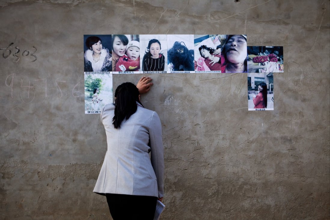 A woman cries looking at the pictures of her dead sister pasted on the wall of her former home in Zhang village, Henan Province, central China. Photo: Getty 
