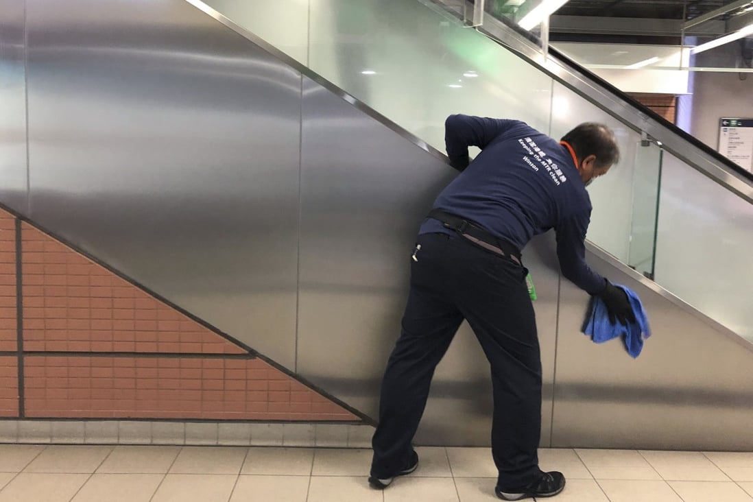 Artist Luke Ching Chin-wai keeping the escalator handrail germ-free at Tai Shui Hang MTR station, part of his latest performance art project to highlight the work of low-paid cleaners on Hong Kong’s subway network. Photo: Enid Tsui