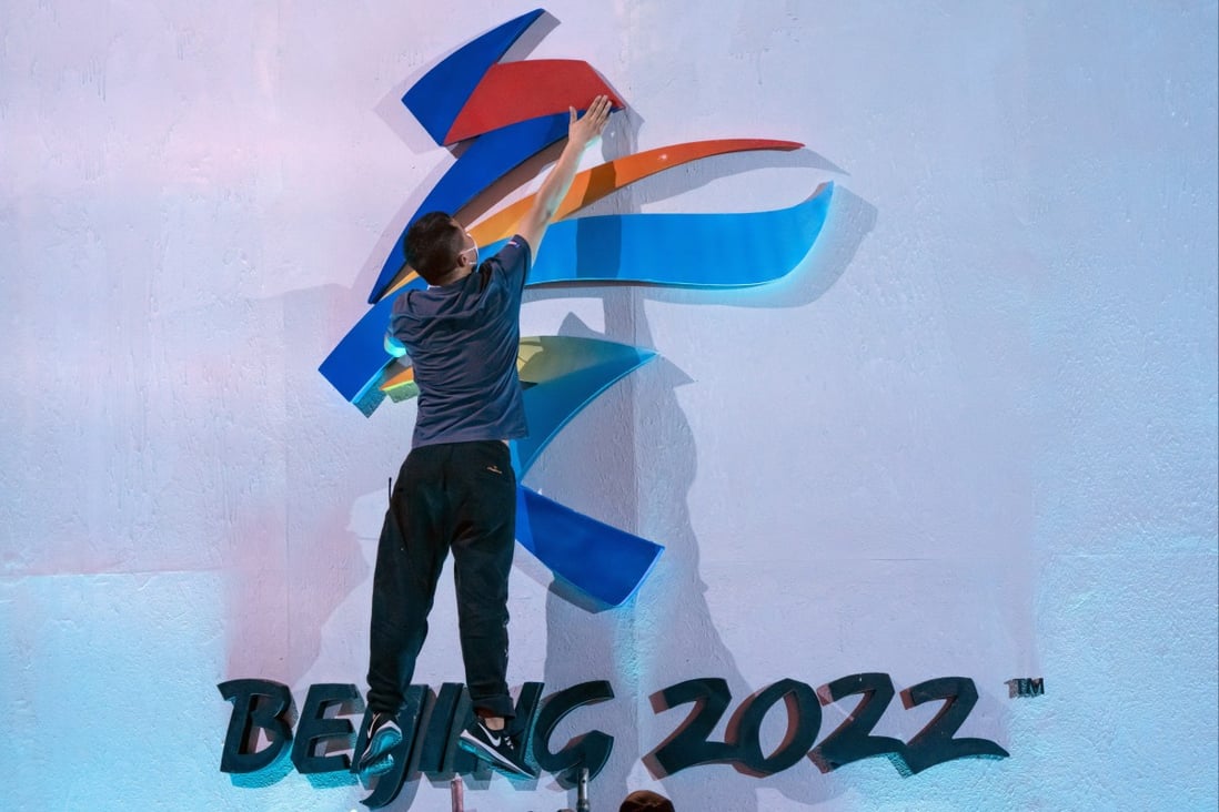 An employee fixes the logo for the 2022 Winter Olympics before an event in Beijing in September. Photo: AP
