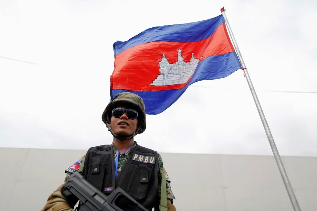 An armed security guard stands under a Cambodian flag in the capital Phnom Penh in November 2012. Photo: Reuters