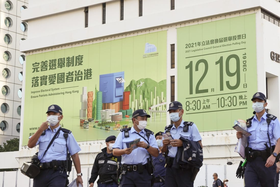 Police in front of a huge banner in Central promoting the Legco poll. Photo: May Tse