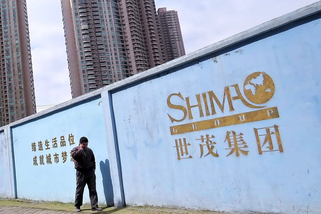 A man talks on his mobile phone outside a construction site of Shimao Group in Shanghai. Photo: VCG
