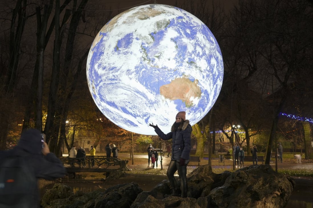 A girl poses by a depiction of the Earth at a light installation by British artist Luke Jerram in Bucharest on Saturday. Romania recently relaxed some of its pandemic restrictions. Photo: AP